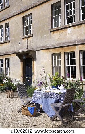 Wooden chairs and table with blue cloth outside old stone country house View Large Photo Image Stock Image - Wooden chairs and table with blue cloth outside old stone country house. Fotosearch