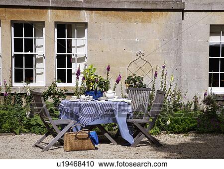 Wooden chairs and table with blue cloth outside old stone country house View Large Photo Image Stock Image - Wooden chairs and table with blue cloth outside old stone country house. Fotosearch