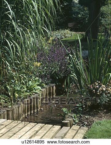 Wooden edging on bank of small stream in country garden View Large Photo Image Stock Photography - Wooden edging on bank of small stream in country garden. Fotosearch