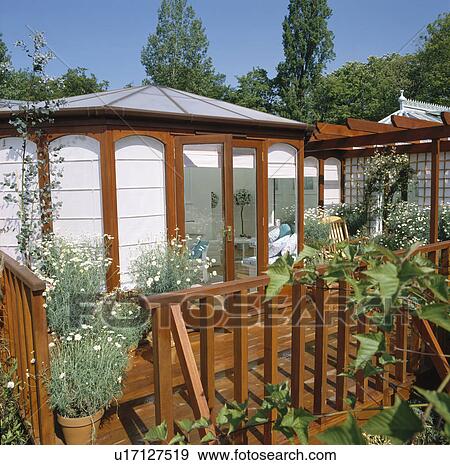 Stock Photo - Wooden fence in front of traditional conservatory with white blinds. Fotosearch