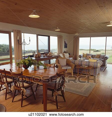 Wooden table and chairs in open-plan coastal dining and living room View Large Photo Image Stock Image - Wooden table and chairs in open-plan coastal dining and living room. Fotosearch