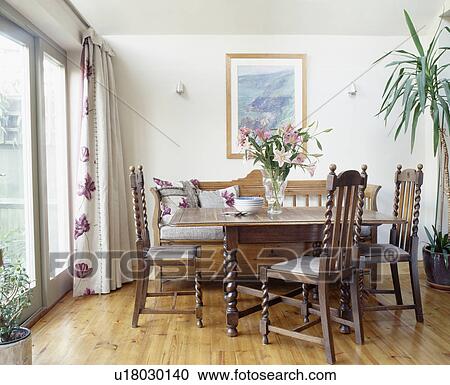 Stock Image - Wooden table and chairs in economy-style dining room with wooden flooring. Fotosearch