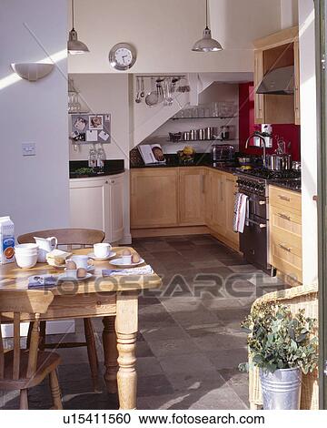 Stock Image - Wooden table and chairs in traditional cottage kitchen. Fotosearch