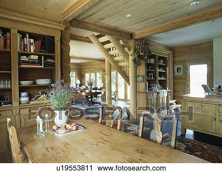 Stock Image - Wooden table in in dining room with wooden ceiling and log panelled walls. Fotosearch