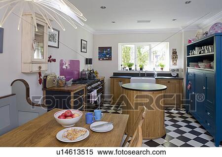 Wooden table in white kitchen with circular island unit and black+white chequerboard flooring View Large Photo Image Stock Photography - Wooden table in white kitchen with circular island unit and black+white chequerboard flooring. Fotosearch