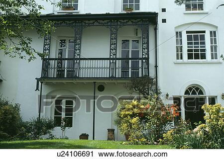 Stock Image - Wrought iron balcony on white Victorian townhouse. Fotosearch