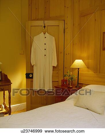 Yellow dress on door of pale wood panelled bedroom View Large Photo Image Stock Photo - Yellow dress on door of pale wood panelled bedroom. Fotosearch