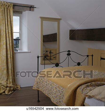 Yellow quilt on iron bed in cottage bedroom with patterned yellow curtain at window View Large Photo Image Picture - Yellow quilt on iron bed in cottage bedroom with patterned yellow curtain at window. Fotosearch