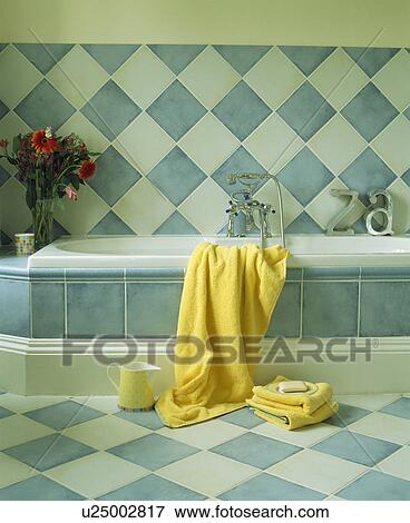 Yellow towel on bath in bathroom with blue+white wall tiles View Large Photo Image Stock Photo - Yellow towel on bath in bathroom with blue+white wall tiles. Fotosearch