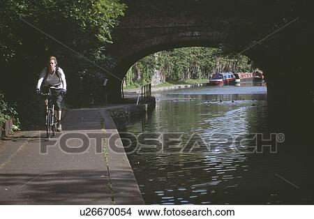 Young woman cycling on towpath beside the Regent Canal in London View Large Photo Image Picture - Young woman cycling on towpath beside the Regent Canal in London. Fotosearch