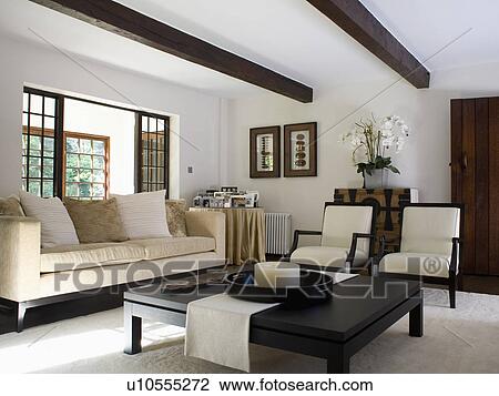 低い 黒 コーヒーテーブル そして クリーム ソファー そして 椅子 中に 現代 白 国の 生活 部屋 ストックイメージ U Fotosearch