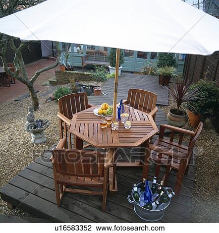 Aerial view of white parasol above wooden table and chairs on patio in town garden View Large Photo Image Stock Image - Aerial view of white parasol above wooden table and chairs on patio in town garden. Fotosearch