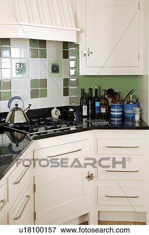 Alessi kettles on hob below white and green tiled wall in kitchen with white fitted units View Large Photo Image Stock Photo - Alessi kettles on hob below white and green tiled wall in kitchen with white fitted units. Fotosearch