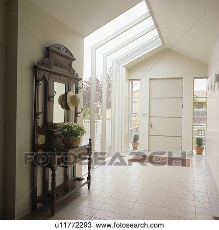 Stock Image - Antique mirror and console table in modern white hall. Fotosearch