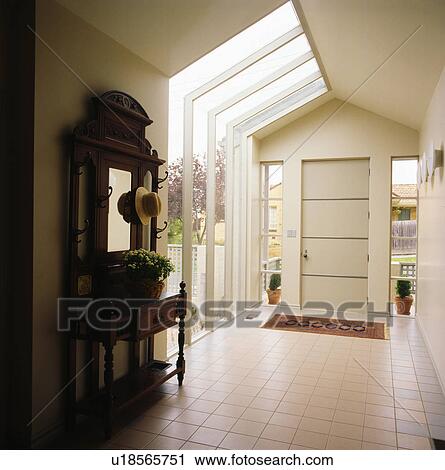 Stock Image - Antique mirror and console table in modern white hall. Fotosearch