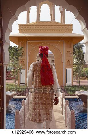 Back view of man in traditional Rajastani clothes crossing footbridge over water at Rajvilas Hotel View Large Photo Image Stock Photograph - Back view of man in traditional Rajastani clothes crossing footbridge over water at Rajvilas Hotel. Fotosearch