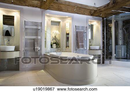Stock Photo - Basins in lighted alcove in large modern bathroom with bath extending into room. Fotosearch