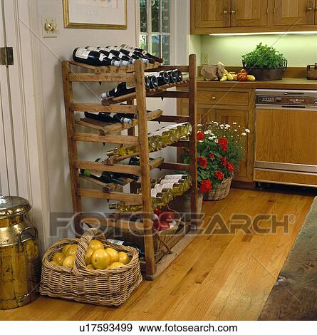 Stock Photo - Basket of grapefruit on floor beside wine bottles stored in old wooden wine rack in country kitchen. Fotosearch