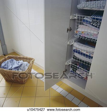 Basket of washing beside cupboard with folded laundry in metal drawers View Large Photo Image Stock Photo - Basket of washing beside cupboard with folded laundry in metal drawers. Fotosearch