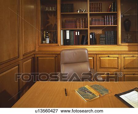 Stock Photo - Beige leather chair at desk in traditional panelled office with fitted bookcase. Fotosearch