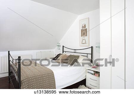 Beige textured throw on black metal bed in modern white attic bedroom View Large Photo Image Stock Photography - Beige textured throw on black metal bed in modern white attic bedroom . Fotosearch