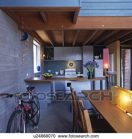 Stock Image - Bicycle against concrete wall in modern kitchen dining room. Fotosearch