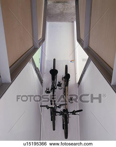 Stock Photograph - Bicycles stored on ceiling in modern hall. Fotosearch