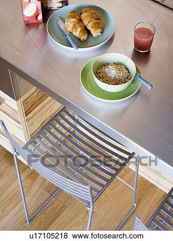 Stock Photo - Birdseye view of metal chair and metal table set for breakfast with croissants and cereal. Fotosearch