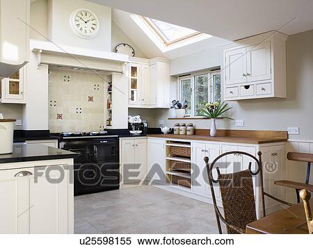 Stock Photography - Black Aga oven in cream country kitchen extension with ceramic flooring. Fotosearch