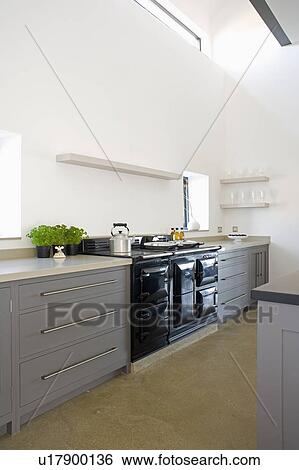 Stock Photograph - Black Aga oven in modern white kitchen with fitted grey units. Fotosearch