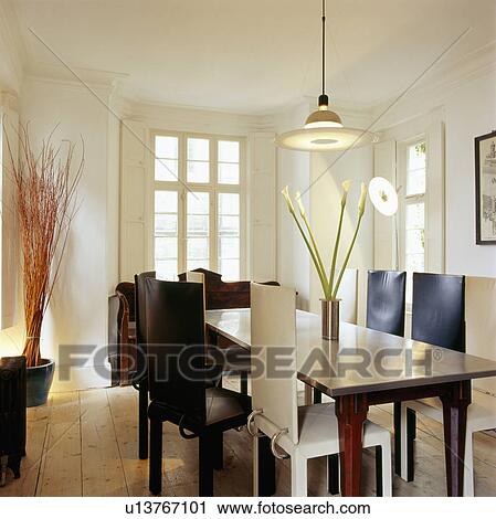 Stock Image - Black and white chairs and stainless steel table in modern dining room. Fotosearch