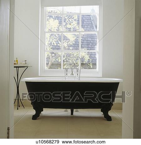 Black clawfoot bath in front of window in white townhouse bathroom View Large Photo Image Stock Photo - Black clawfoot bath in front of window in white townhouse bathroom. Fotosearch