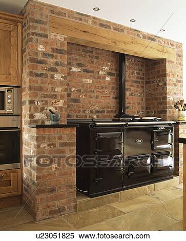 Stock Photography - Black double Aga oven in exposed brick wall in country kitchen. Fotosearch