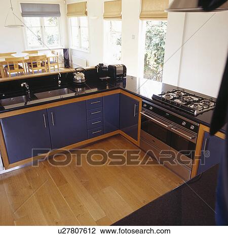 Stock Image - Black fitted units in modern openplan kitchen with range oven. Fotosearch