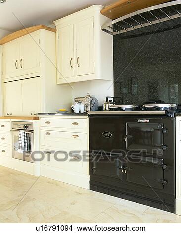 Black granite wall behind black Aga in traditional country kitchen with fitted units painted in cream Farrow+Ball paint View Large Photo Image Picture - Black granite wall behind black Aga in traditional country kitchen with fitted units painted in cream Farrow+Ball paint. Fotosearch