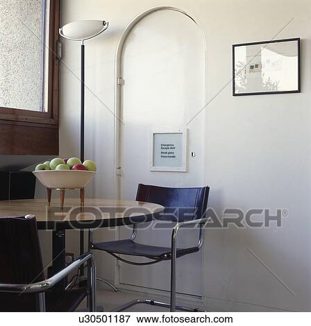 Stock Photo - Black leather and chrome chairs and small wooden table in apartment dining room. Fotosearch