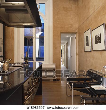Stock Photo - Black Marcel Breuer Wassily chairs in modern kitchen with rough plaster walls. Fotosearch