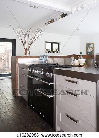 Stock Image - Black range oven in modern white kitchen extension. Fotosearch