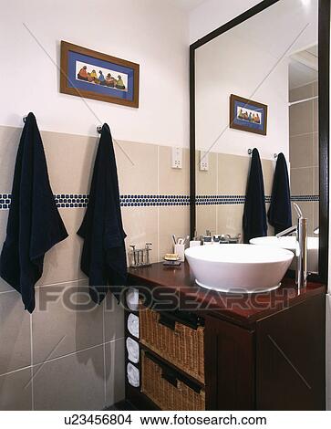 Picture - Black towels on hooks beside white basin on wooden vanity unit in modern bathroom. Fotosearch