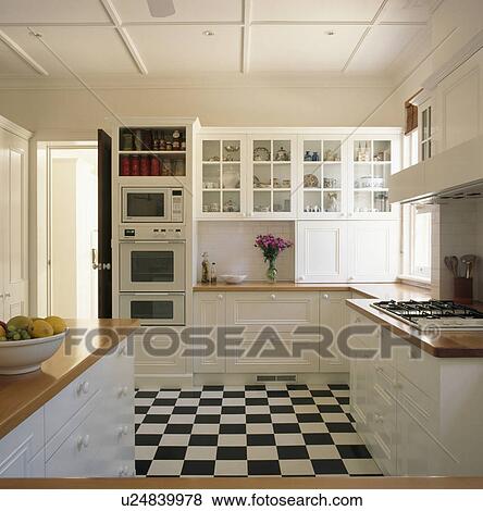Black+white chequerboard flooring in white traditional kitchen View Large Photo Image Stock Photo - Black+white chequerboard flooring in white traditional kitchen. Fotosearch