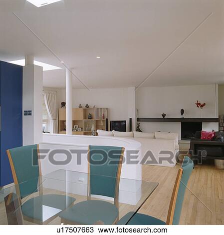 Stock Image - Blue chairs and glass-topped table in open-plan dining and living room. Fotosearch