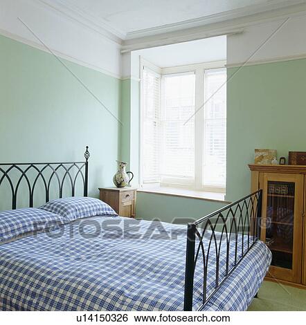 Blue checked bedlinen on metal bed in pastel green bedroom View Large Photo Image Stock Photograph - Blue checked bedlinen on metal bed in pastel green bedroom. Fotosearch