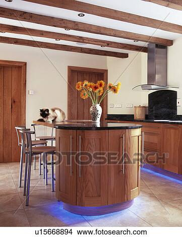 Blue halogen lighting below fitted units in modern country kitchen with beamed ceiling and island unit View Large Photo Image Picture - Blue halogen lighting below fitted units in modern country kitchen with beamed ceiling and island unit. Fotosearch