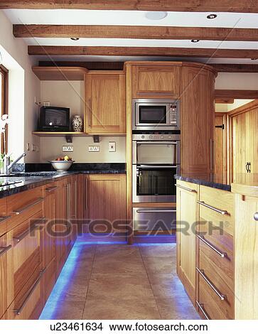 Blue halogen lighting below fitted units in modern country kitchen with beamed ceiling View Large Photo Image Picture - Blue halogen lighting below fitted units in modern country kitchen with beamed ceiling . Fotosearch