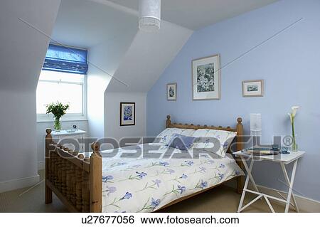 Blue iris-patterned quilt and pillow on bed in pastel blue attic bedroom with white bedside table View Large Photo Image Stock Photograph - Blue iris-patterned quilt and pillow on bed in pastel blue attic bedroom with white bedside table. Fotosearch
