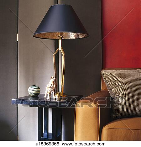 Stock Photography - Blue metallic lamp on small black table beside ochre yellow silk sofa. Fotosearch