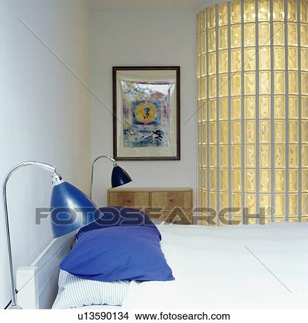 Blue metallic lamps and blue cushions on bed in modern bedroom with glass brick wall View Large Photo Image Picture - Blue metallic lamps and blue cushions on bed in modern bedroom with glass brick wall. Fotosearch