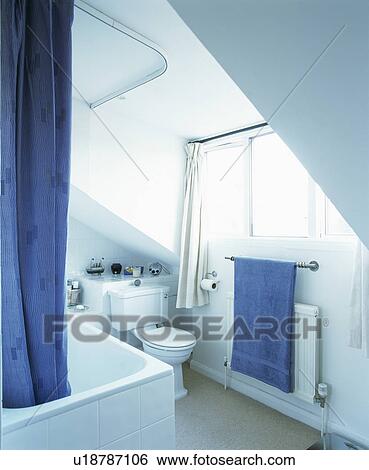 Stock Photograph - Blue shower curtain and towel in white bathroom. Fotosearch