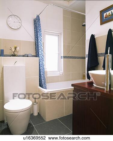 Stock Image - Blue shower curtain on bath in modern white bathroom. Fotosearch