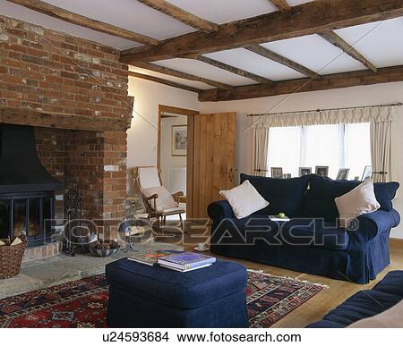Blue sofa and ottomanl in beamed cottage living room with exposed brick fireplace View Large Photo Image Picture - Blue sofa and ottomanl in beamed cottage living room with exposed brick fireplace. Fotosearch
